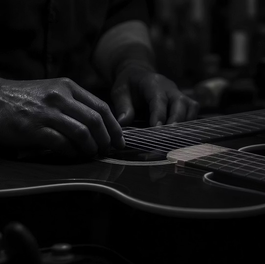 Black-and-white close-up of hands on an acoustic guitar
